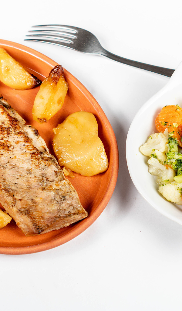 Кусок запеченной рыбы на тарелке с овощами 