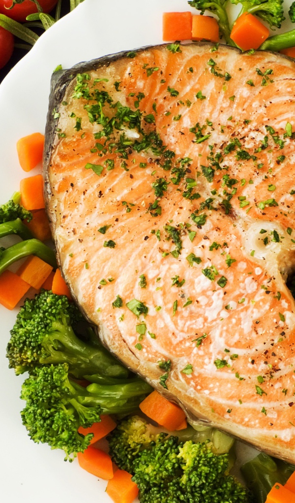 A piece of red fish on a plate with carrots and broccoli