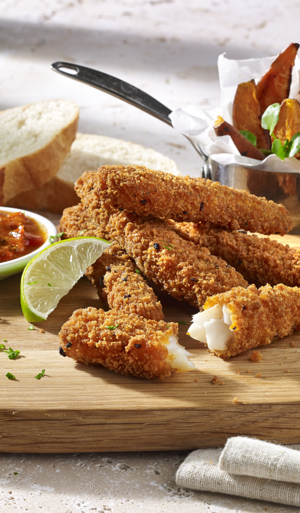 Рыба в панировке на столе с соусом и кусочками лайма
