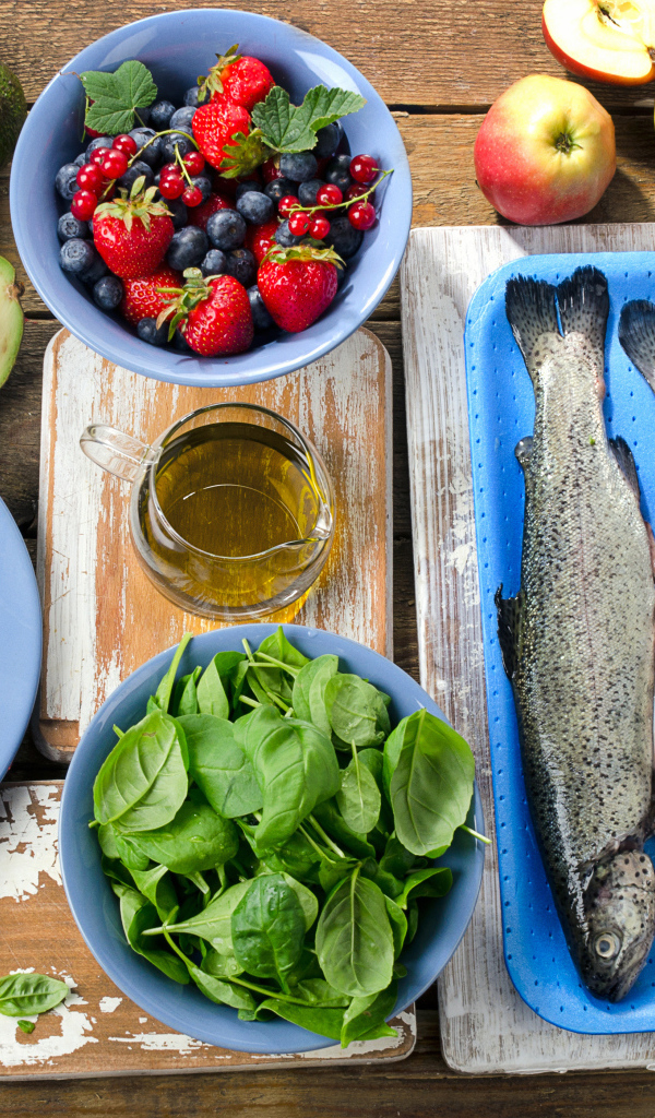 Fresh fish on a table with nuts, basil and berries