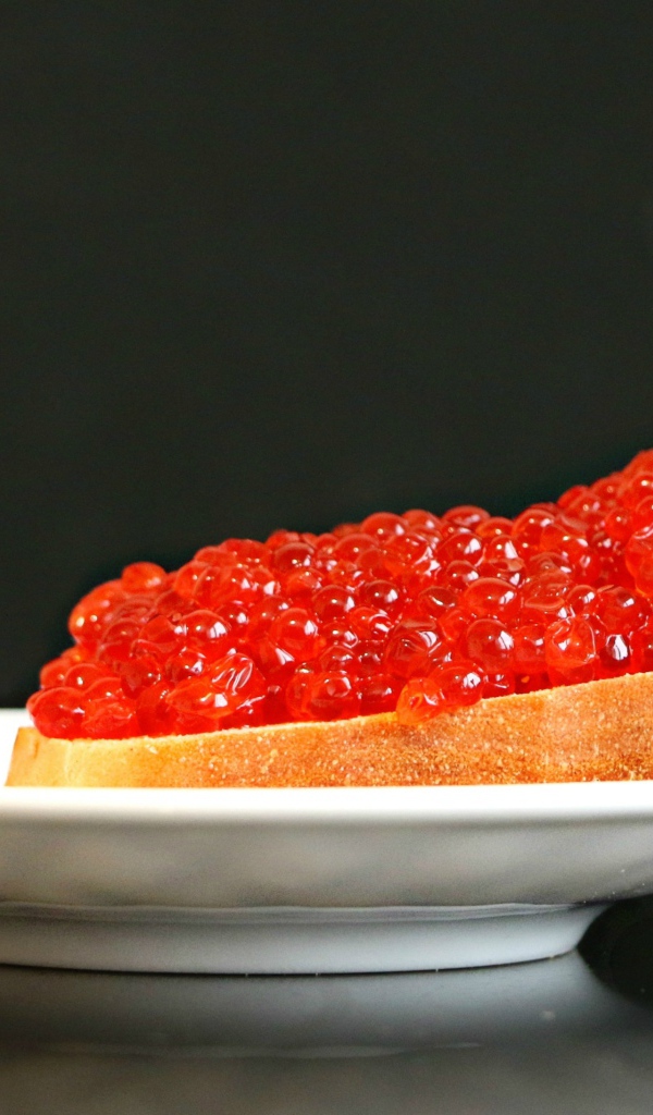 Бутерброд с красной икрой на белой тарелке 