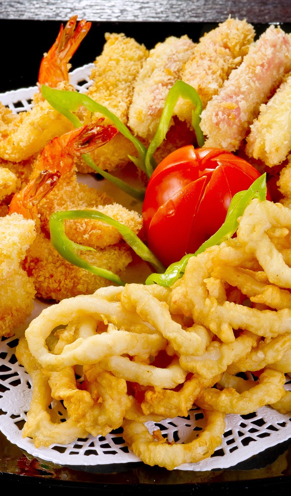 Морепродукты в кляре на тарелке с помидором