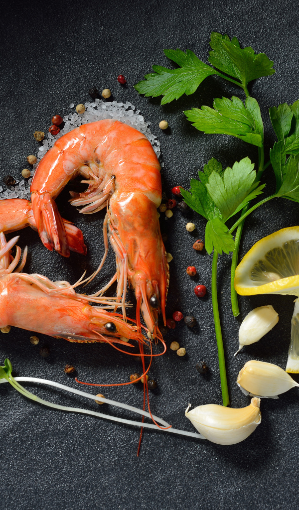 Сердце из креветок на сером столе с лимоном и веточкой петрушки 