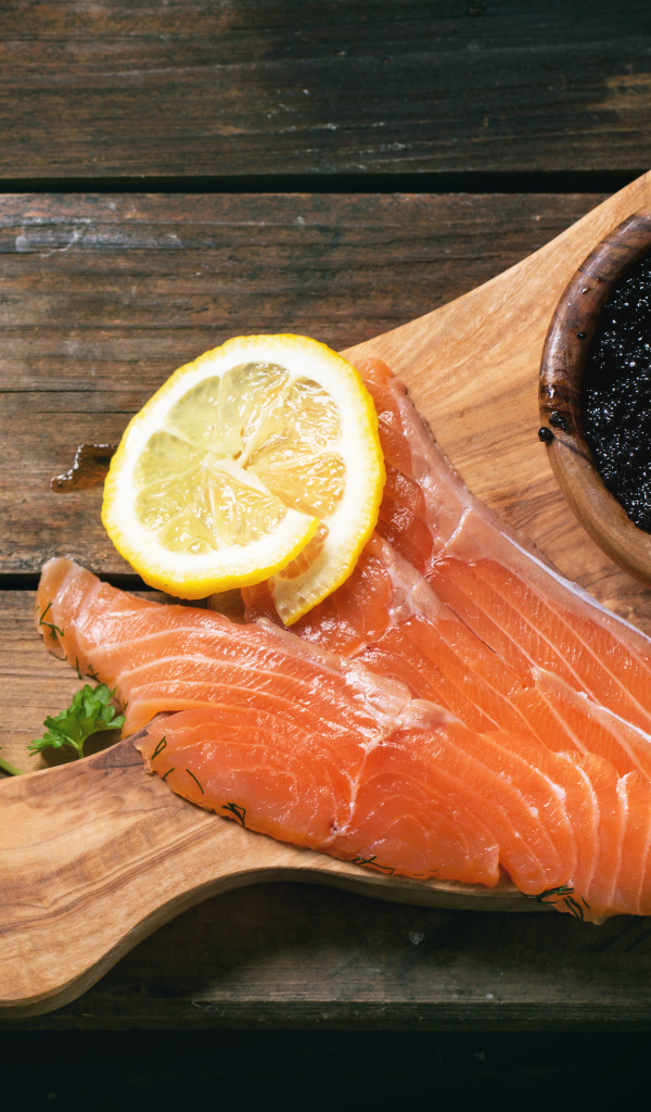 Кусочки красной рыбы с лимоном на столе с черной икрой 