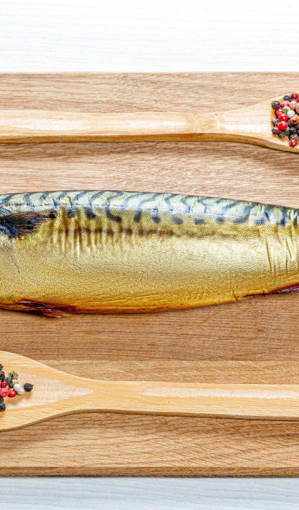 Копченая скумбрия на разделочной доске с перцем на белом фоне