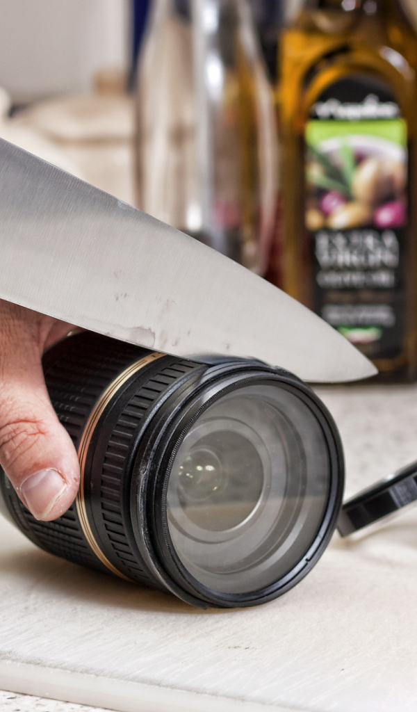 A man cuts a camera lens with a knife