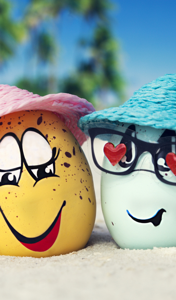 Два яйца в шляпах на песке с морскими звездами летом