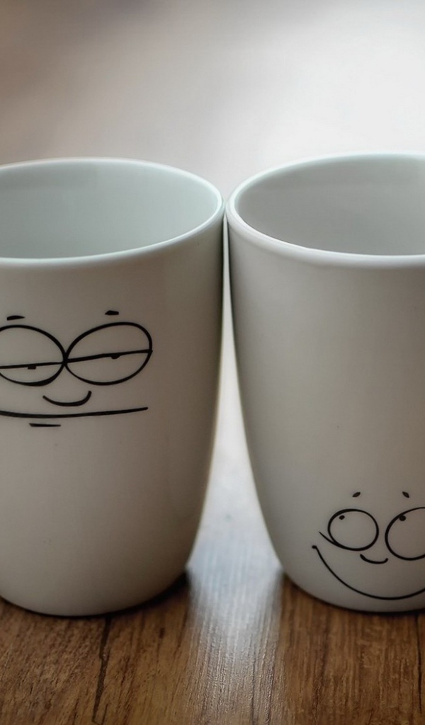 Две белые кружки с рисунками на столе 