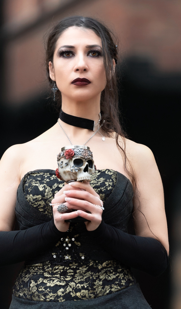 Девушка готка с бокалом - черепом в руках 