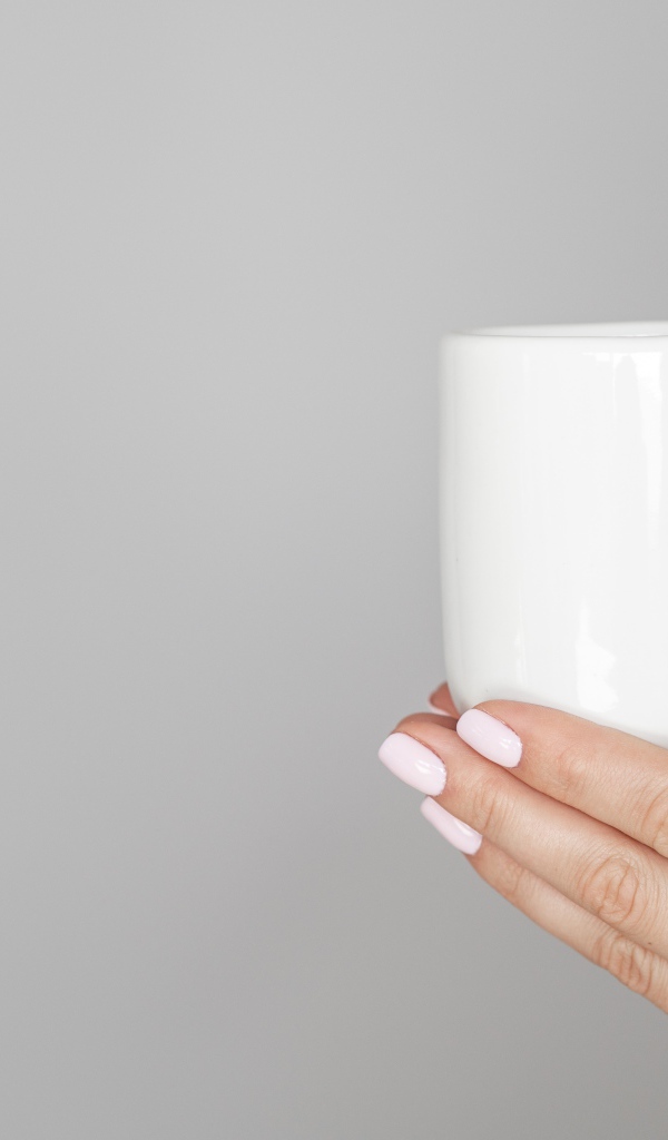 Белая кружка в руках девушки на сером фоне