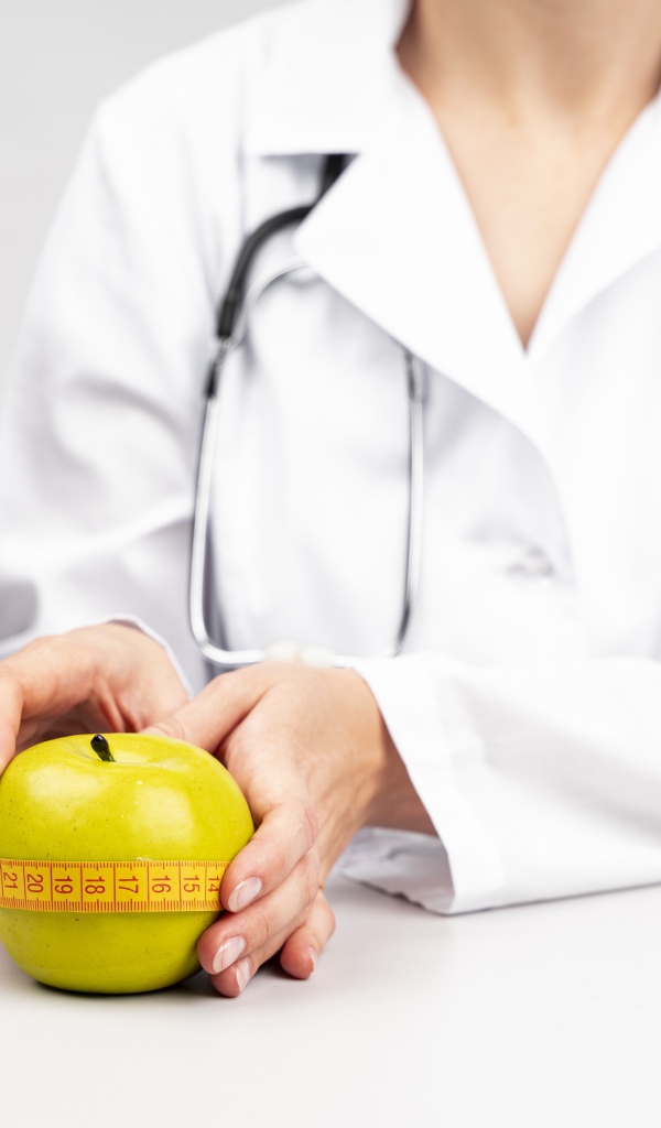 Woman doctor measures an apple with a centimeter