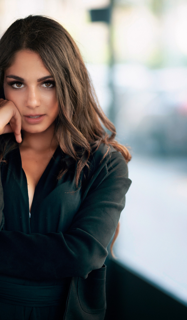 Милая девушка в черном наряде стоит на остановке