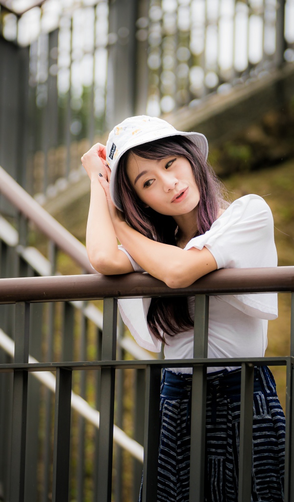 Молодая девушка азиатка стоит на лестнице у перил 