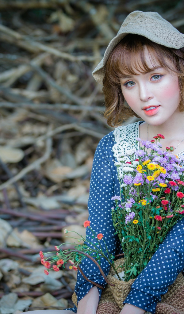 Молодая девушка азиатка с букетом цветов сидит на ветках