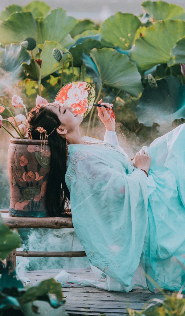 Девушка азиатка в красивом голубом платье на поле лотосов