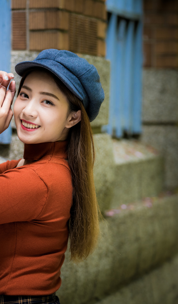 Девушка азиатка в кепке на стенке 