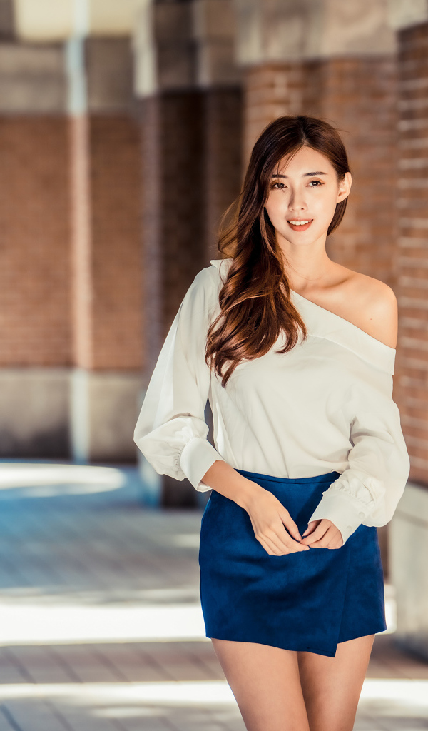 Девушка азиатка в короткой юбке у стены