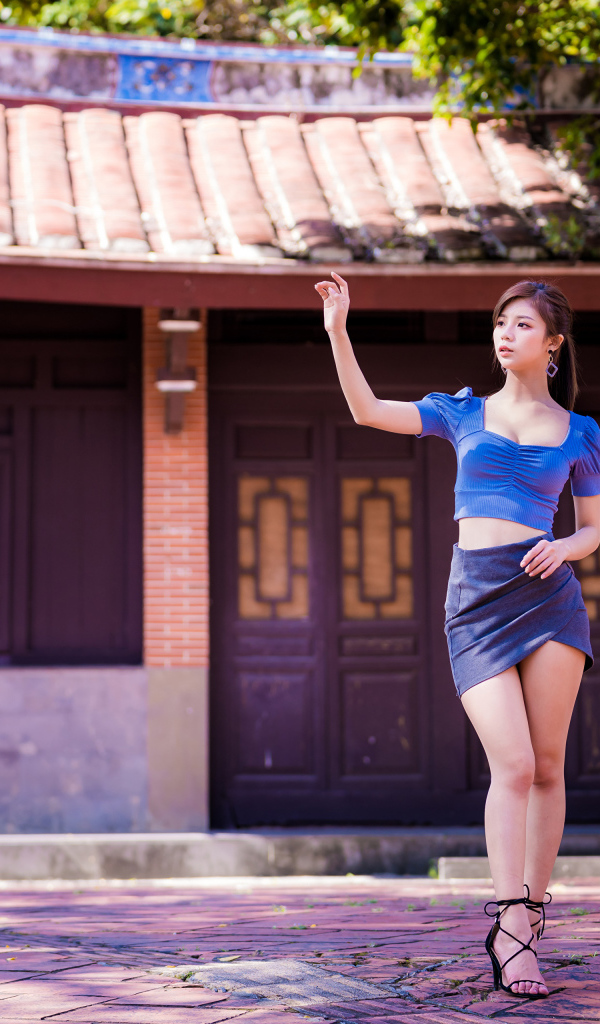 Девушка азиатка в короткой юбке у здания 