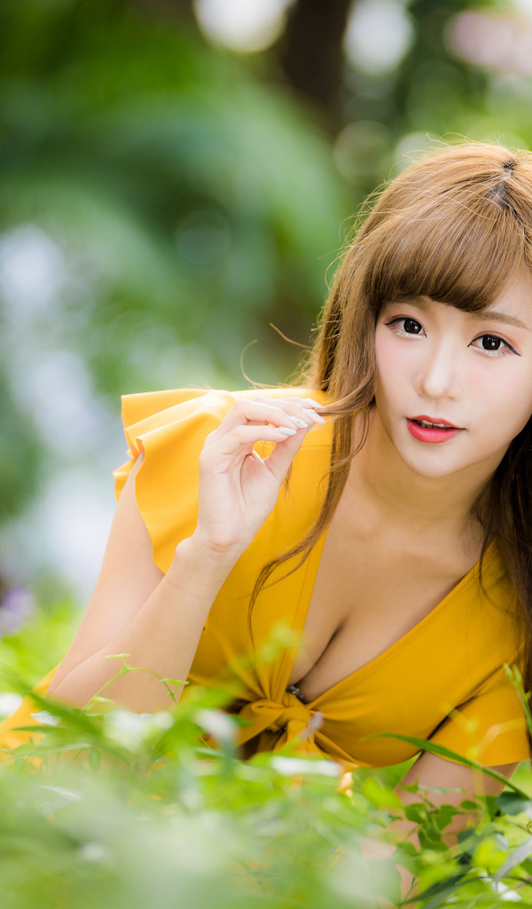 Девушка азиатка в желтом платье в парке 