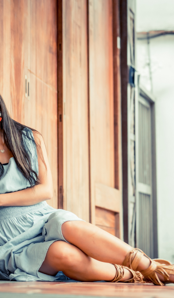 Девушка азиатка в платье сидит на полу у стены 