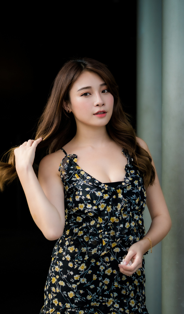 Девушка азиатка в платье трогает волосы 