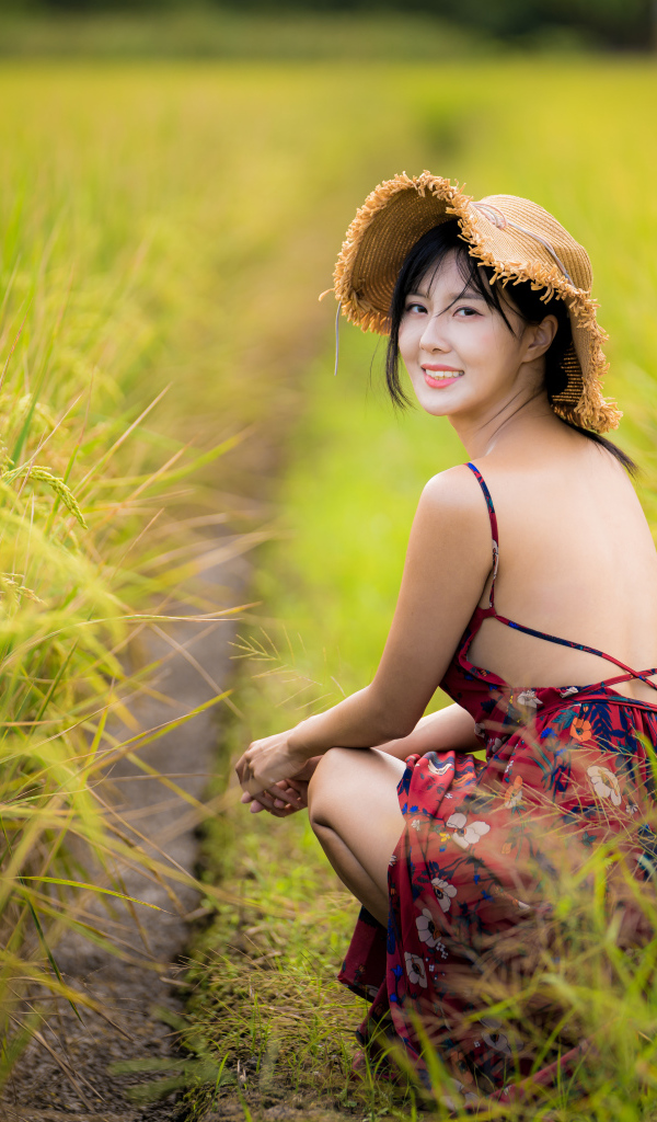 Девушка азиатка сидит на рисовом поле 