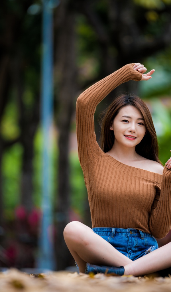 Девушка азиатка сидит в позе лотоса в парке 