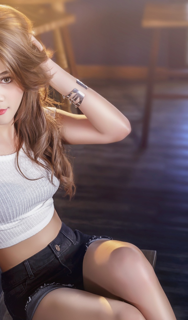 Девушка азиатка сидит на деревянном стуле в кафе