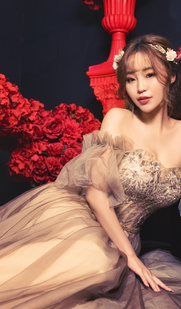 Азиатка в красивом платье в комнате с красными цветами