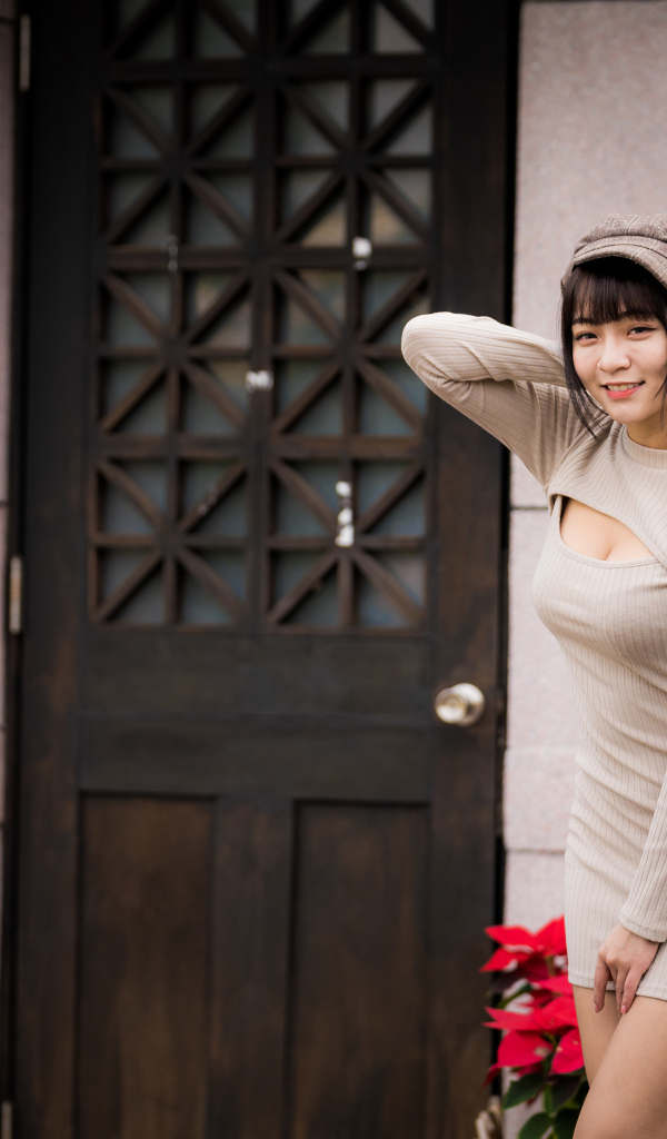 Красивая азиатка в платье стоит у двери 