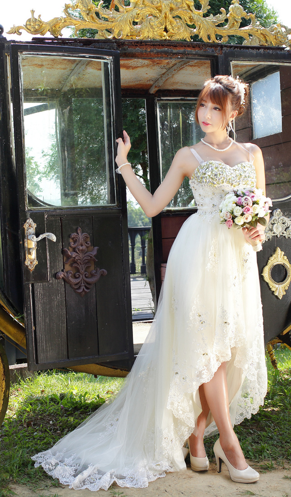 Красивая девушка азиатка в свадебном платье у кареты 