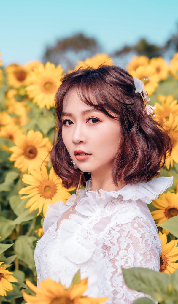 Красивая девушка азиатка в белом платье на поле с подсолнухами