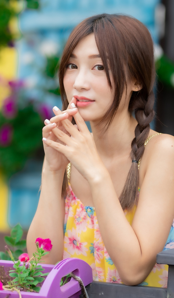 Красивая девушка Азиатка у цветов петунии