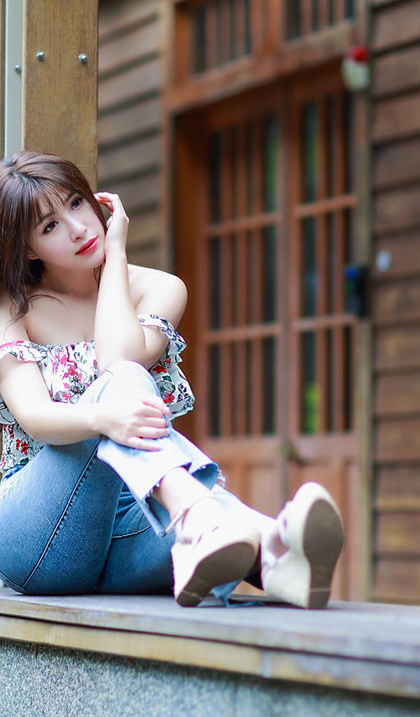 Красивая девушка азиатка сидит у дома