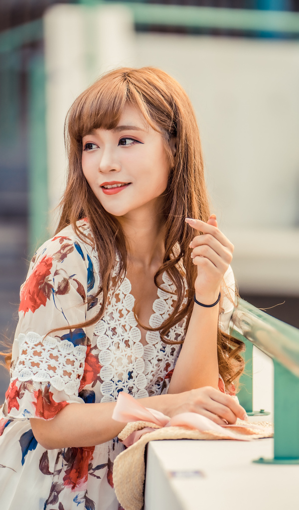 Красивая девушка азиатка стоит у перил 