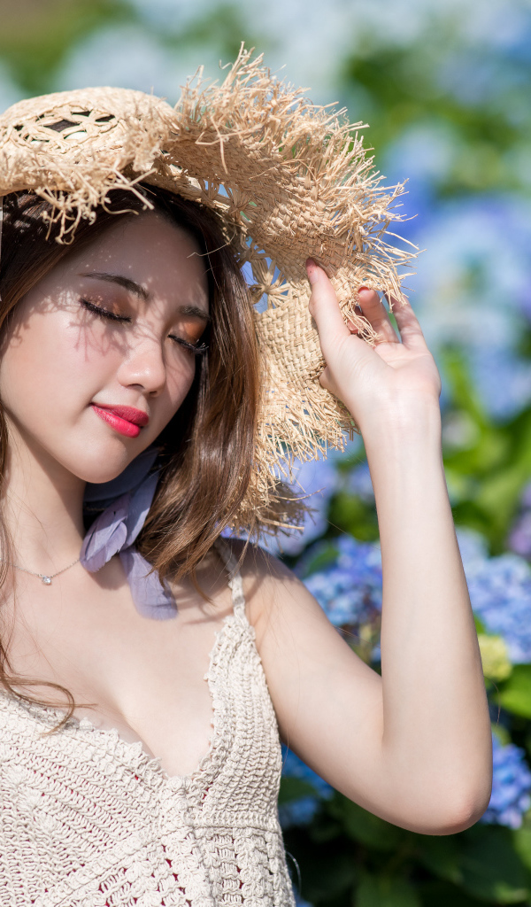 Красивая девушка азиатка с закрытыми глазами на фоне цветов гортензии