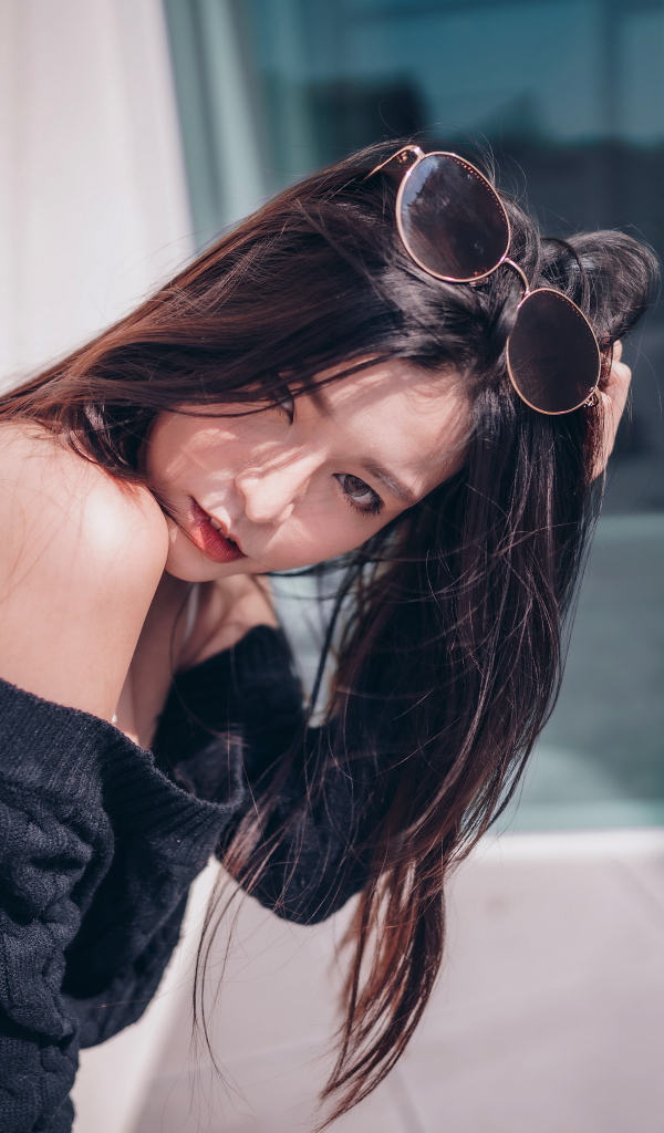 Красивая азиатка в черном свитере с солнечными очками на голове 