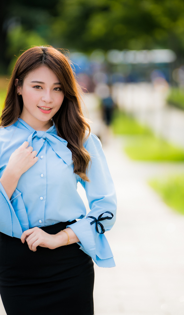 Красивая азиатка в голубой блузке и черной юбке 