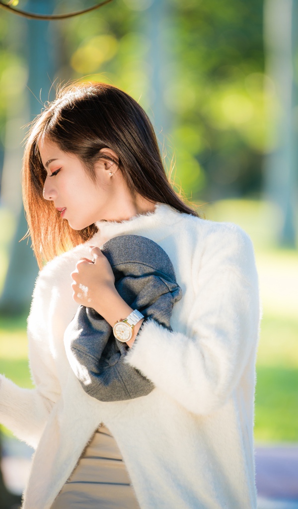 Красивая азиатка в белой кофте в солнечном парке