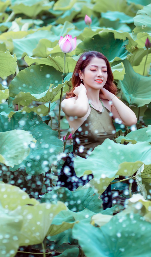 Красивая девушка азиатка в зеленых листьях лотоса 