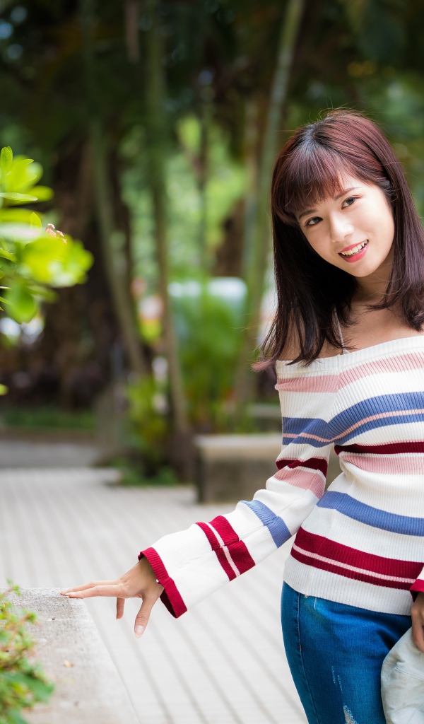 Красивая азиатка в полосатом свитере в парке