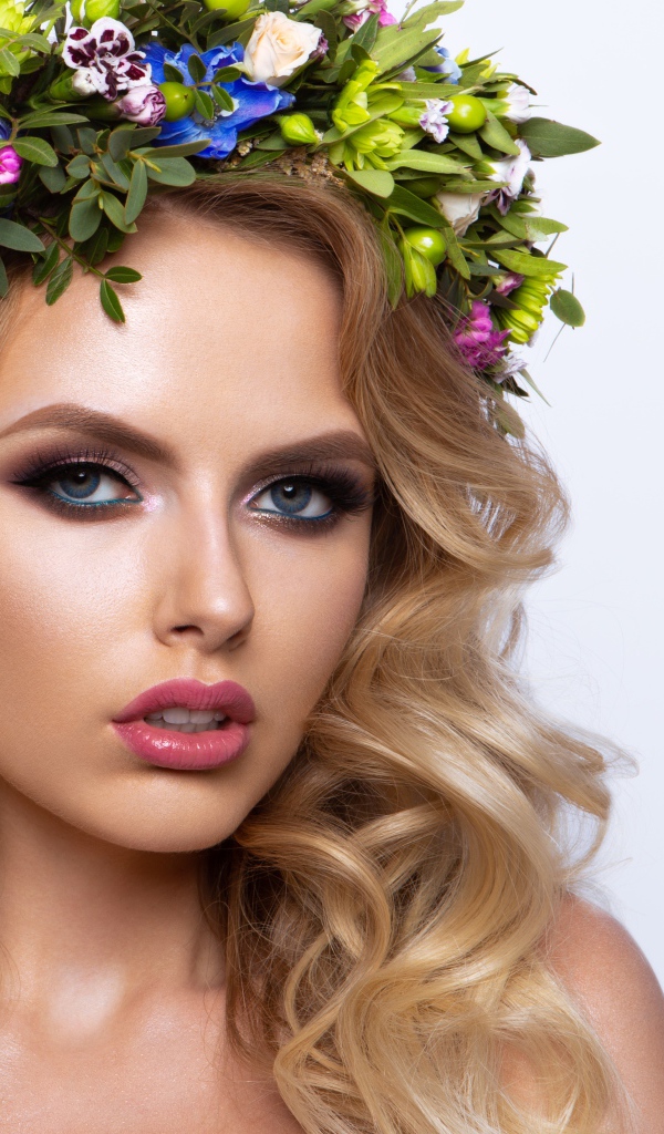 Красивая блондинка с венком из живых цветов на белом фоне