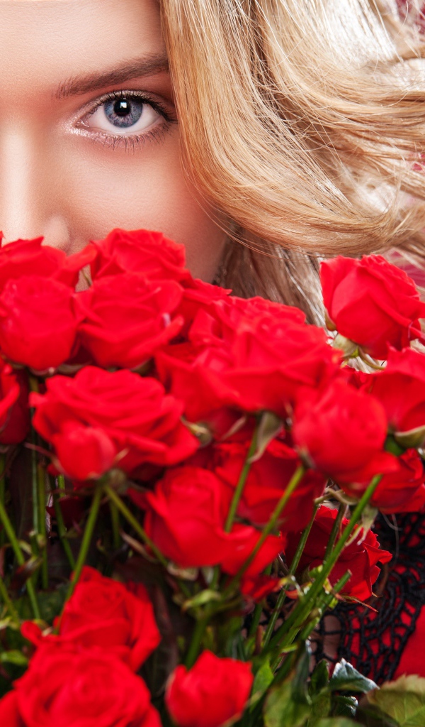 Красивая голубоглазая блондинка с букетом красных роз 