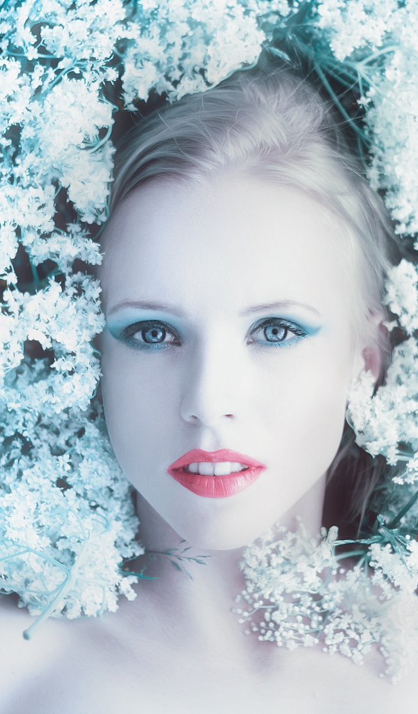 Красивая голубоглазая девушка на траве с белыми цветами