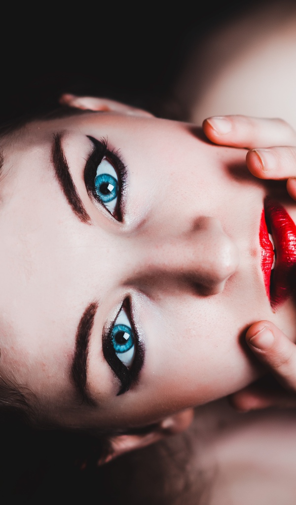 Красивая голубоглазая девушка с красными губами смотрит вверх 