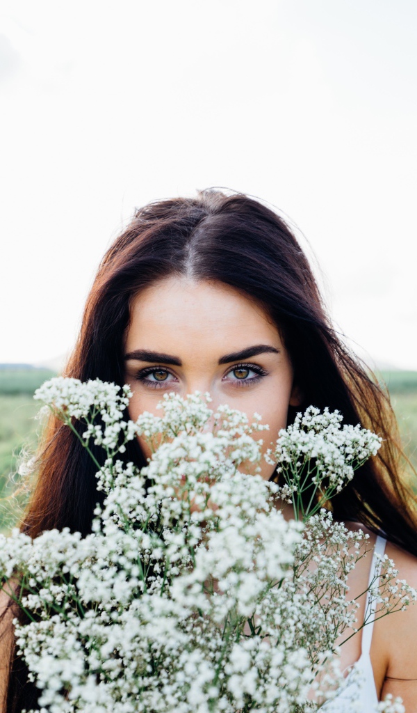 Красивая кареглазая девушка с букетом белых полевых цветов 