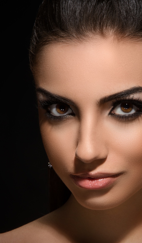 Красивая кареглазая девушка с прической на черном фоне