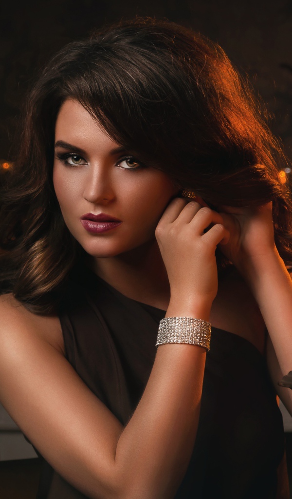 Красивая брюнетка в черном платье и зажженными свечами