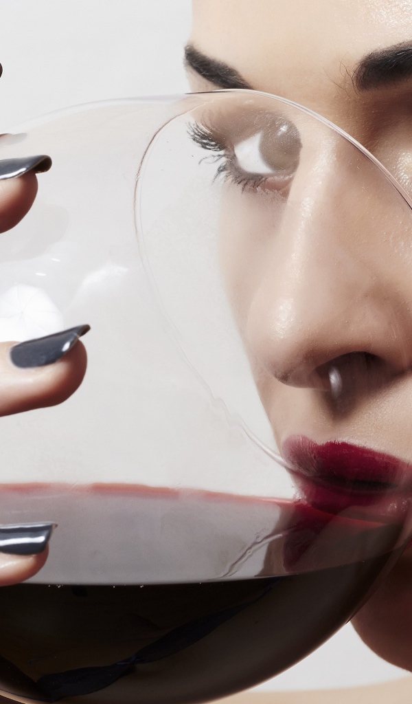 Красивая девушка пьет вино из бокала 