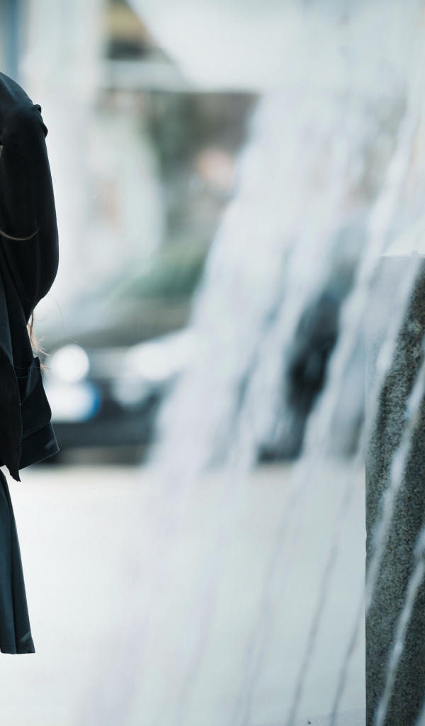 Красивая девушка в черном платье с руками на голове 